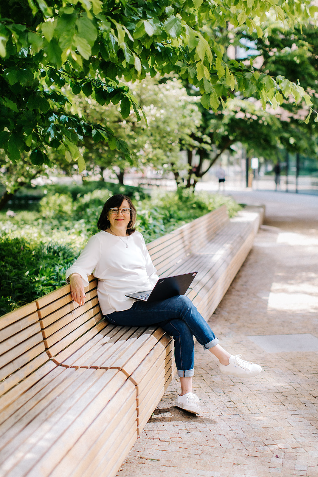 Jana Bodáková working on a laptop on a park bench